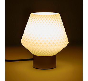 Glass lamp with a diamond pattern shade turned on in a dark space