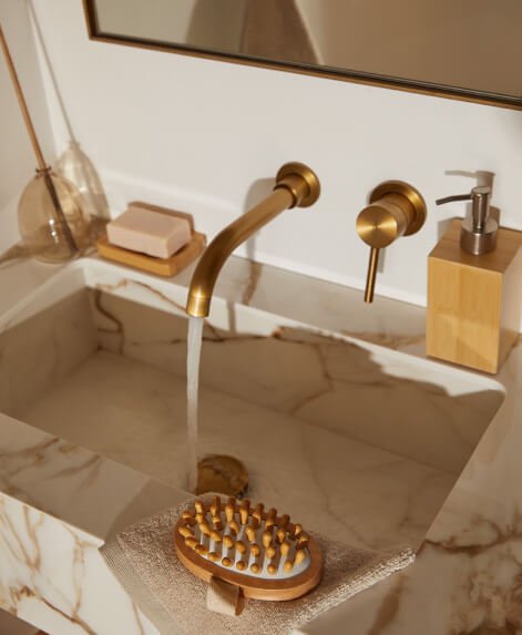 A neutral sink with a bamboo soap dispenser, soap block and other acessories