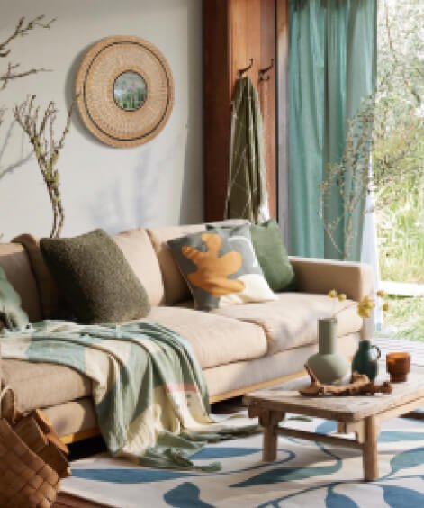 A neutral sofa with a selection of tonal cushions and blankets in a living room