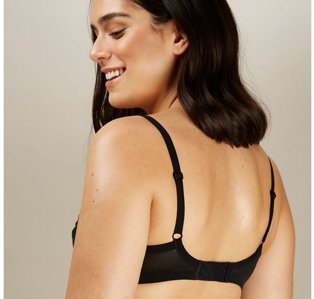 Reverse shot of woman looking down wearing black bra.