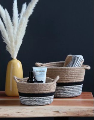 Wooden-effect table features two striped storage baskets and an artificial plant in yellow vase.