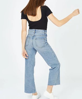 Woman wearing black top and wide legged denim jeans.