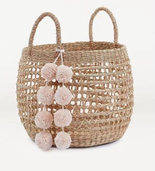 Brown rattan-effect storage basket with pink pom-pom detailing.