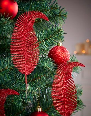 Artificial Christmas tree features red feather baubles and red glitter baubles.