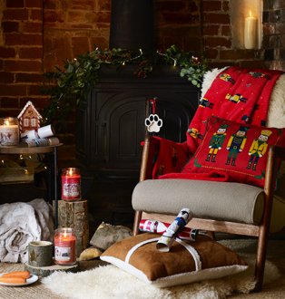 Room features rocking chair topped with novelty throw surrounded by festive candles, crackers and assorted soft furnishings.