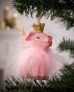 Pink flying pig bauble with glitter crown hanging from tree.
