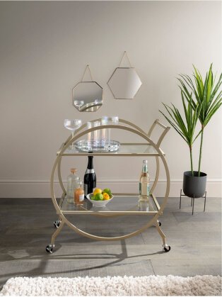 Gold-tone drinks trolly topped with assortment of iridescent glasses, bowl of lemon and limes and selection of drinks bottles.
