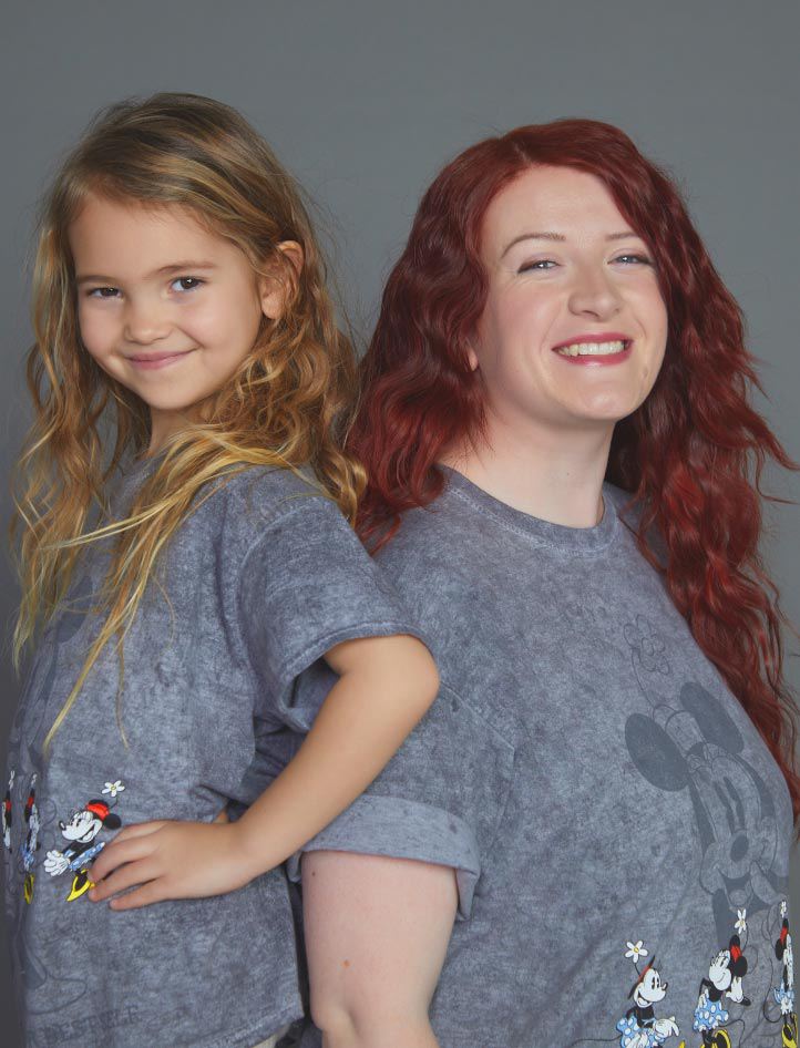 A woman and a child wearing matching Disney t-shirts.