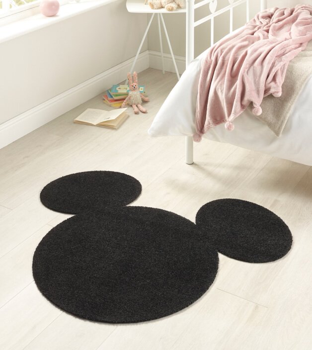 A Mickey Mouse shaped rug in a bedroom