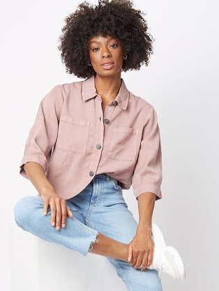 Woman wearing light wash relaxed fit cropped jeans with a purple shirt and white trainers