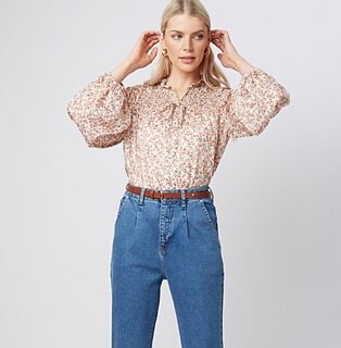 Woman wearing relaxed fit jeans with a printed blouse and brown belt