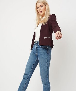 Woman wearing relaxed fit jeans with a white top and burgundy blazer