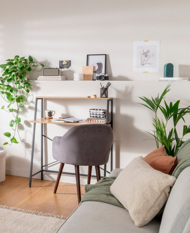 A grey chair at a desk. Plants and home accessories.