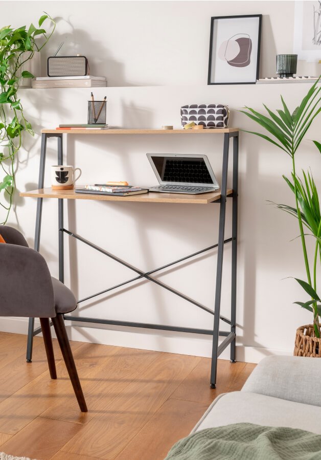 An office desk with a laptop and desk accessories on top.