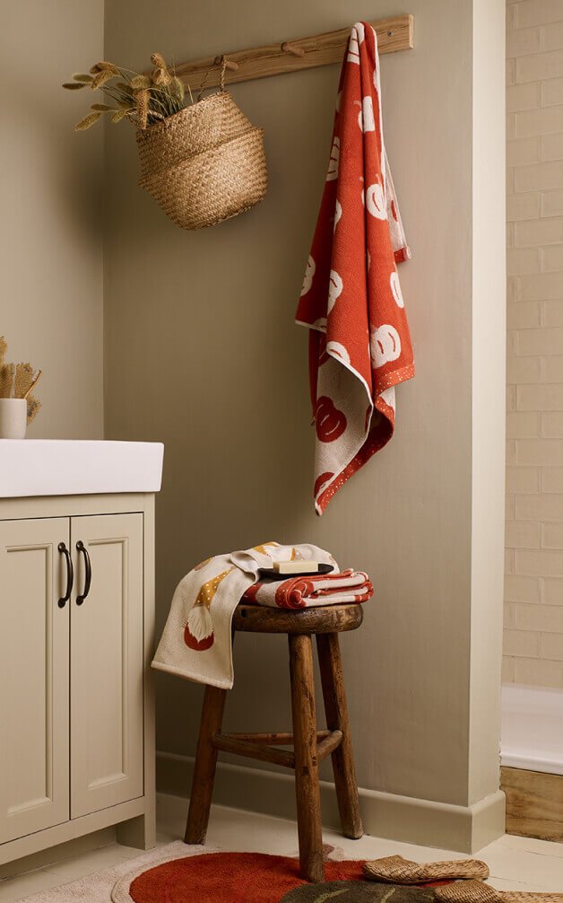 A bathroom stool with patterned orange and white towels.