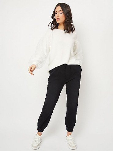 Woman in white long sleeve top, black bottoms and white trainers