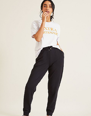 Woman in white and orange slogan t-shirt with black joggers