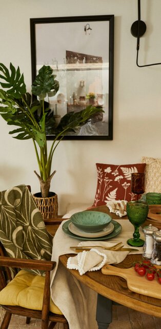 A dining table topped with reactive glaze crockery, green and brown tortoiseshell glasswear and white napkins.