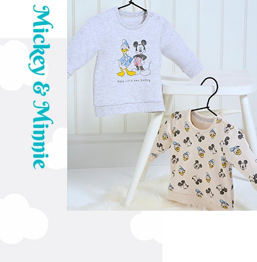 Two Disney jumpers with Donald Duck and Mickey Mouse designs hanging from a white chair on black hangers.