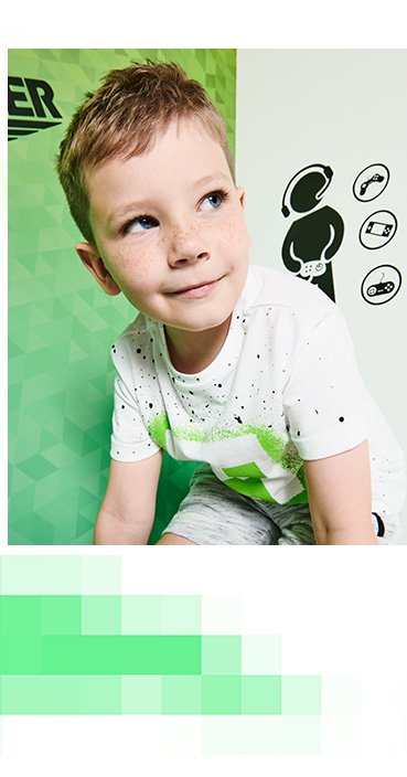 A crouching boy wearing a Minecraft Creeper white logo splatter t-shirt