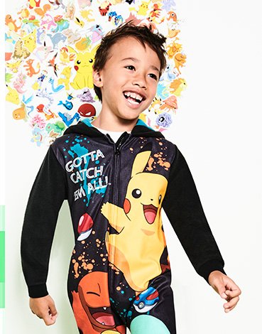 A boy wearing a black Pokémon onesie with Pikachu, Charmander and Squirtle