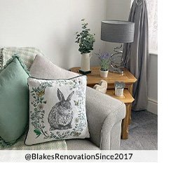 A grey sofa with a selection of cushions on top, including a grey one, green one and bunny print one