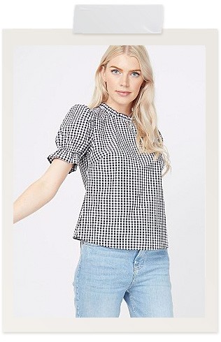Woman wearing a black gingham ruffle blouse and light wash jeans