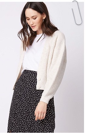 Woman wearing a black and white spotted skirt with a white t-shirt and stone cropped cardigan cardigan
