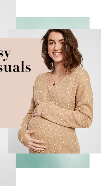 Pregnant woman holding her bump wearing a knitted v neck polka dot jumper