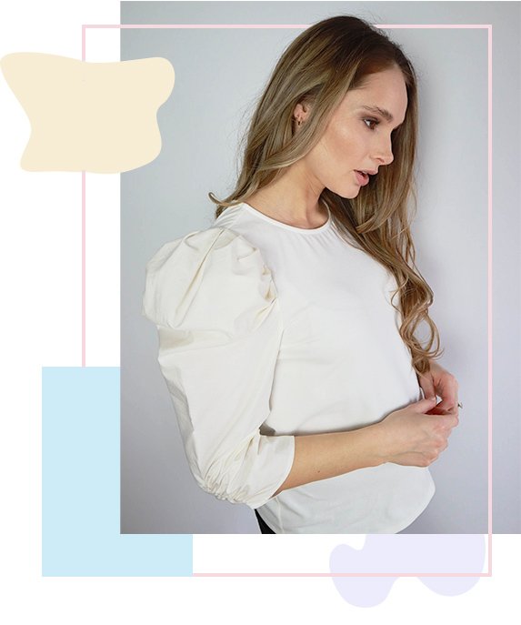 Side profile of woman wearing white long sleeved blouse with ruched shoulders. 