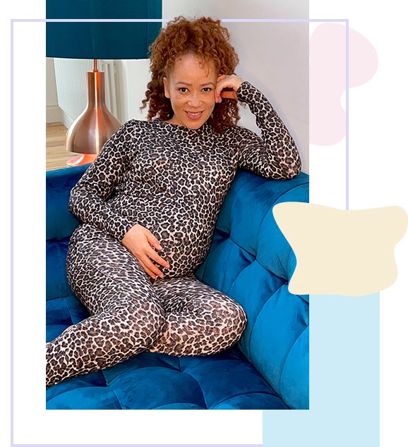 Woman sits with feet up on blue sofa smiling wearing grey leopard print matching long-sleeved top and leggings.