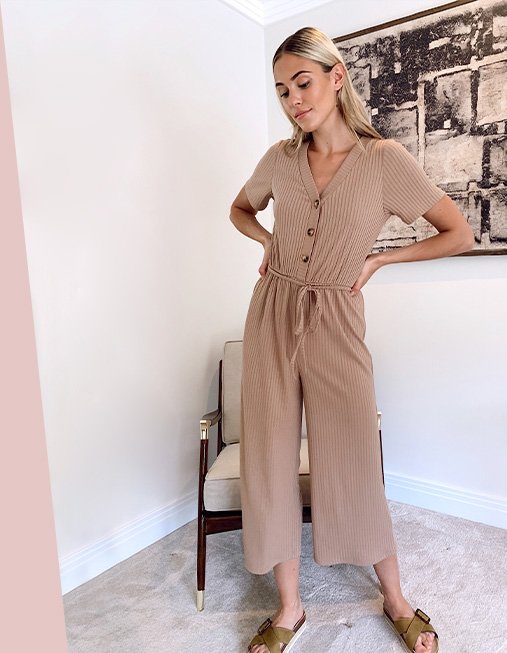 Model Meg wearing a brown jumpsuit with tie waist and buttons