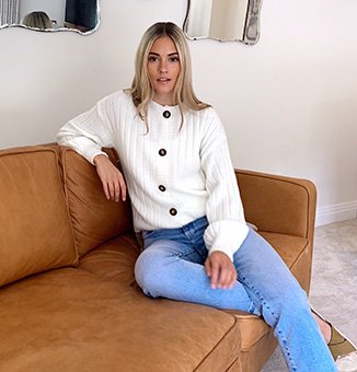 Model Meg wearing a white button up cardigan with light blue jeans