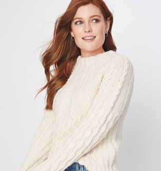 A woman wearing a cream embellished cable knit jumper.