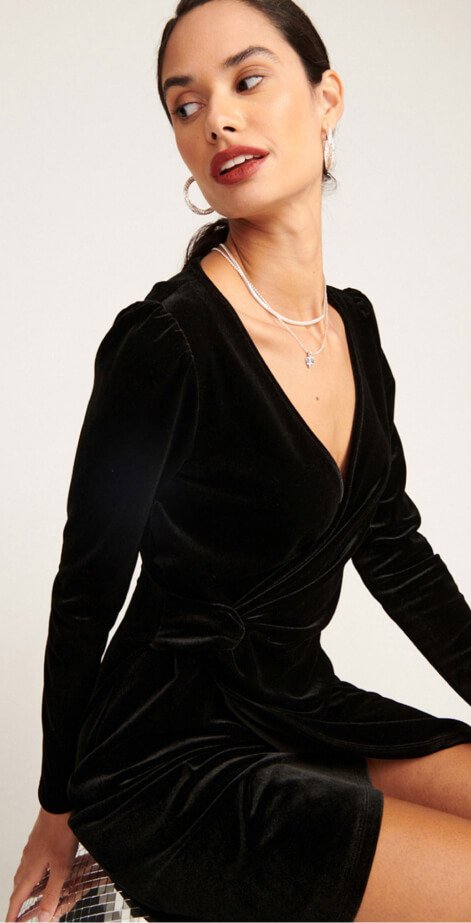 A woman posing in a black velour dress.