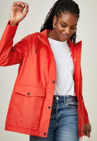 Woman wearing orange parka over white t-shirt and jeans.