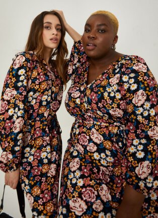 Two women wearing floral printed dresses.