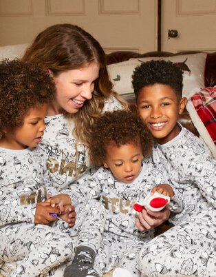 Family of mother and three children in matching Snoopy pyjamas.