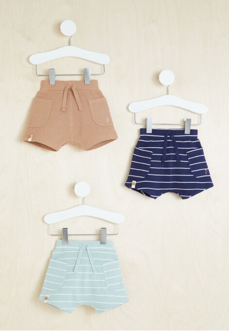Three pairs of shorts hanging on hangers.