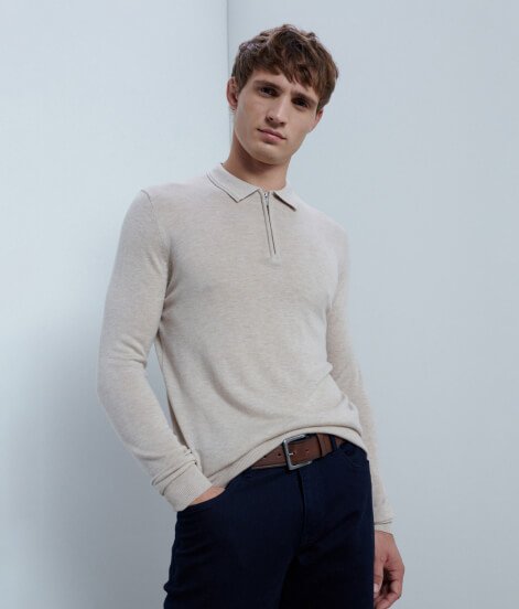Man wearing beige jumper and black trousers.