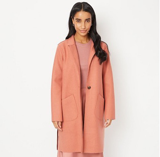 Woman wearing salmon pink longline coat over a pink top and matching skirt