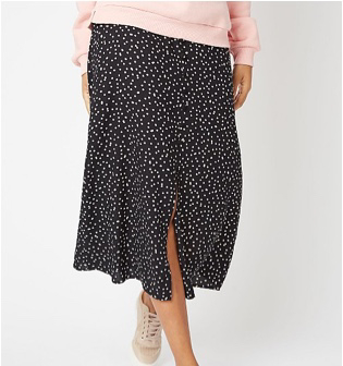 Woman wearing a black polka dot skirt and beige trainers