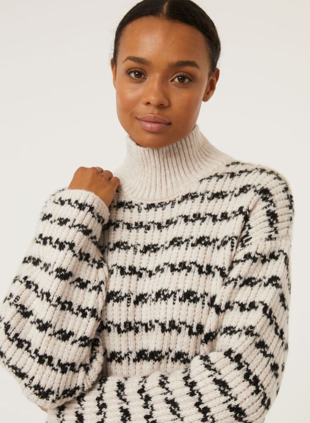 A woman posing in a black and white striped jumper