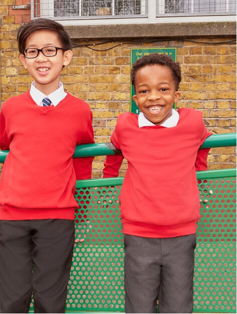 Two boys wearing red school jumpers and black and grey school trousers.
