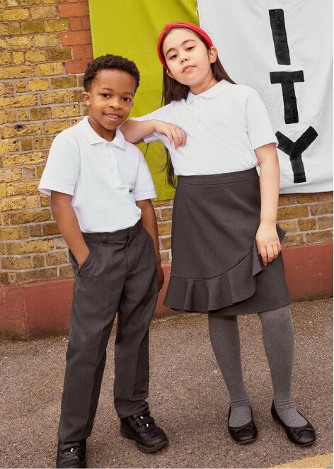 A boy wearing a white polo and grey trousers. A girl wearing a white polo, a grey skirt and grey tights.