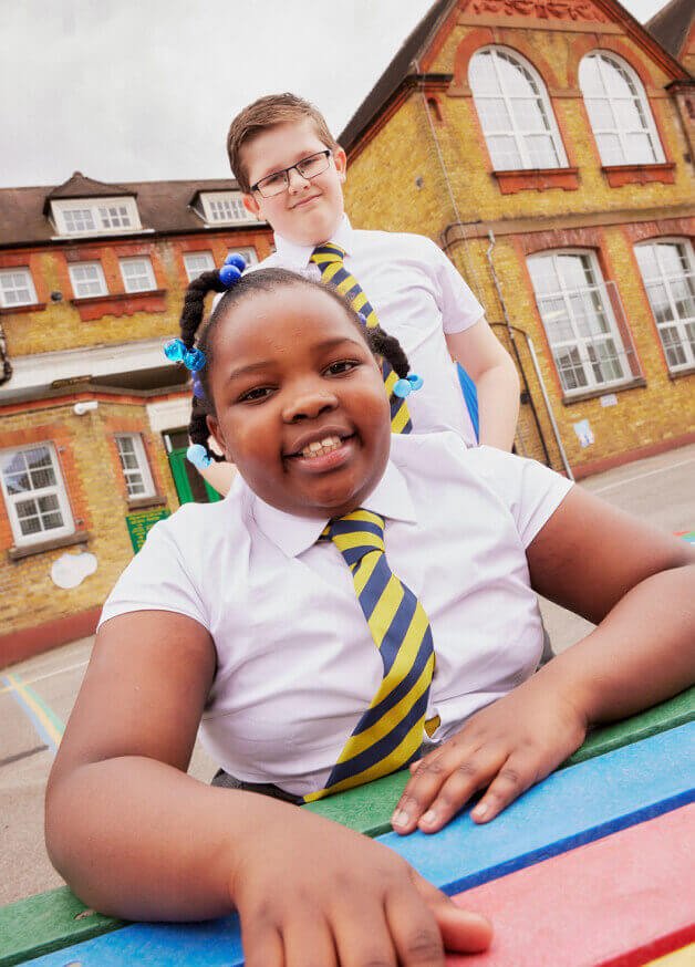 Two children wearing school shirts and ties.