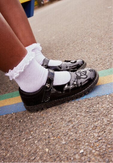 A child wearing patent school shoes and white socks.