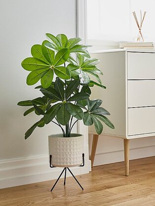 Artificial plant in a white planter on black metal stand