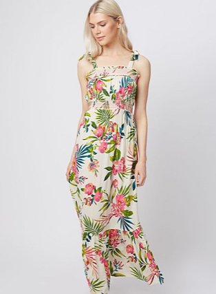 Woman poses looking down wearing multicoloured floral tiered hem midi dress.