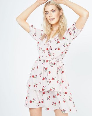 Woman poses raising hands to head wearing light pink floral print ruffle mini dress.